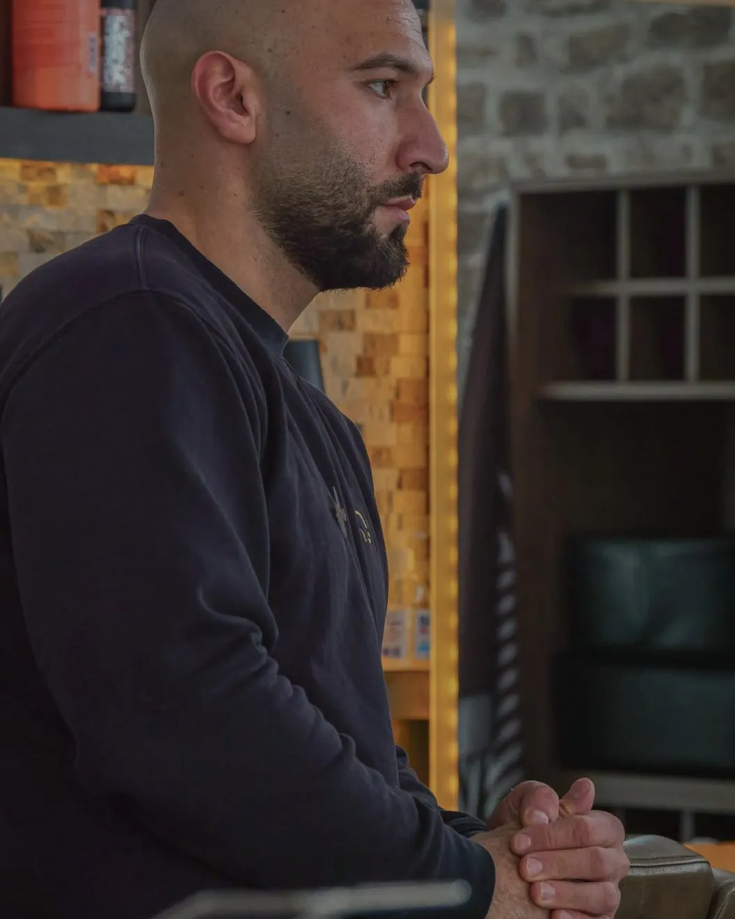 Deno (Deniz Sakin), Inhaber von Deno's Barbersalon, im warmen Licht seines Salons