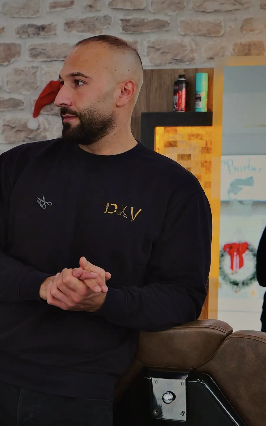 Deno lehnt am Barberstuhl seines Salons